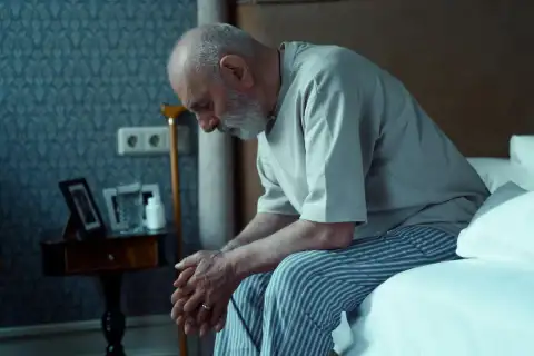 Professional morning care support helping elderly client with safe mobility from bed